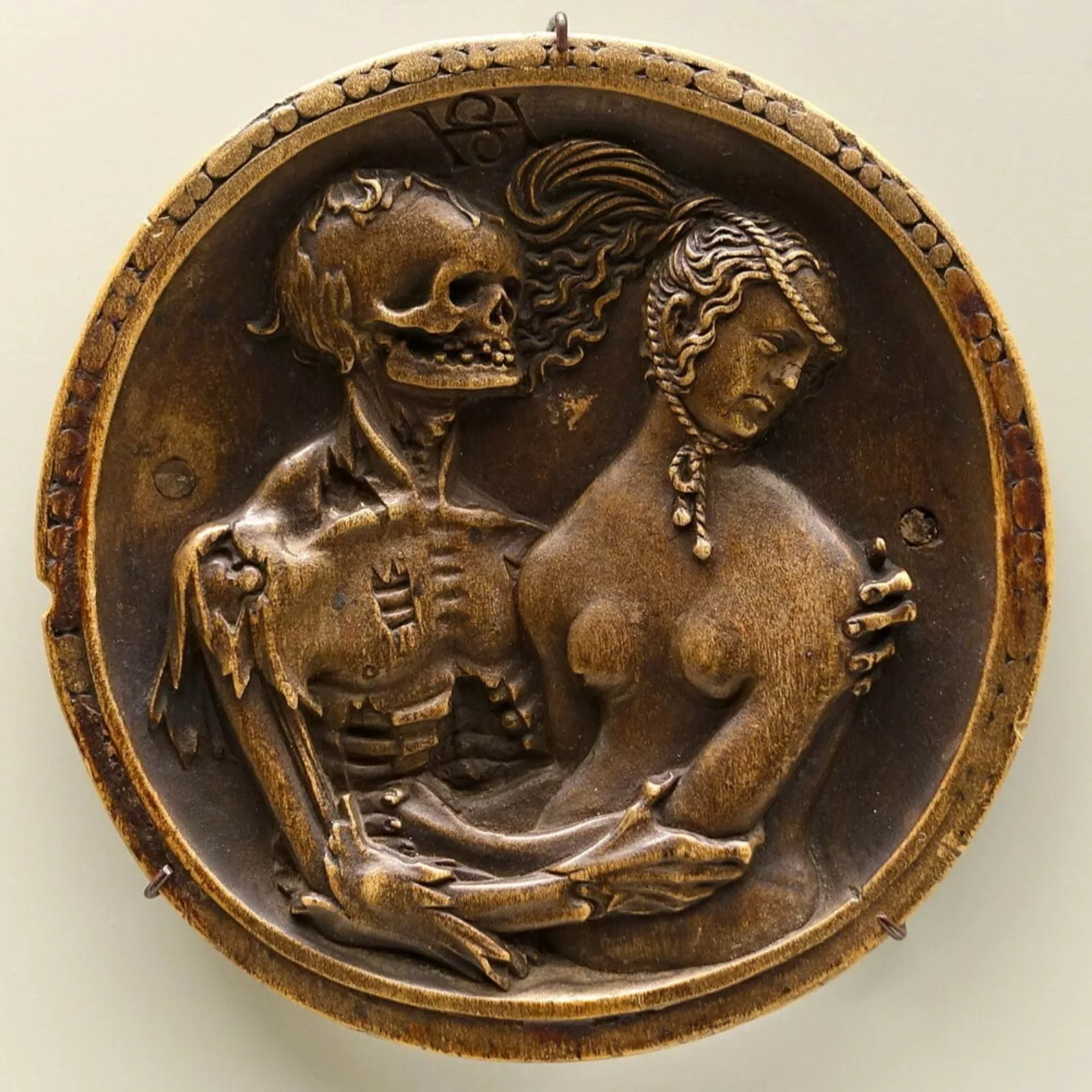 A boxwood carving depicting a skeleton holding a woman.