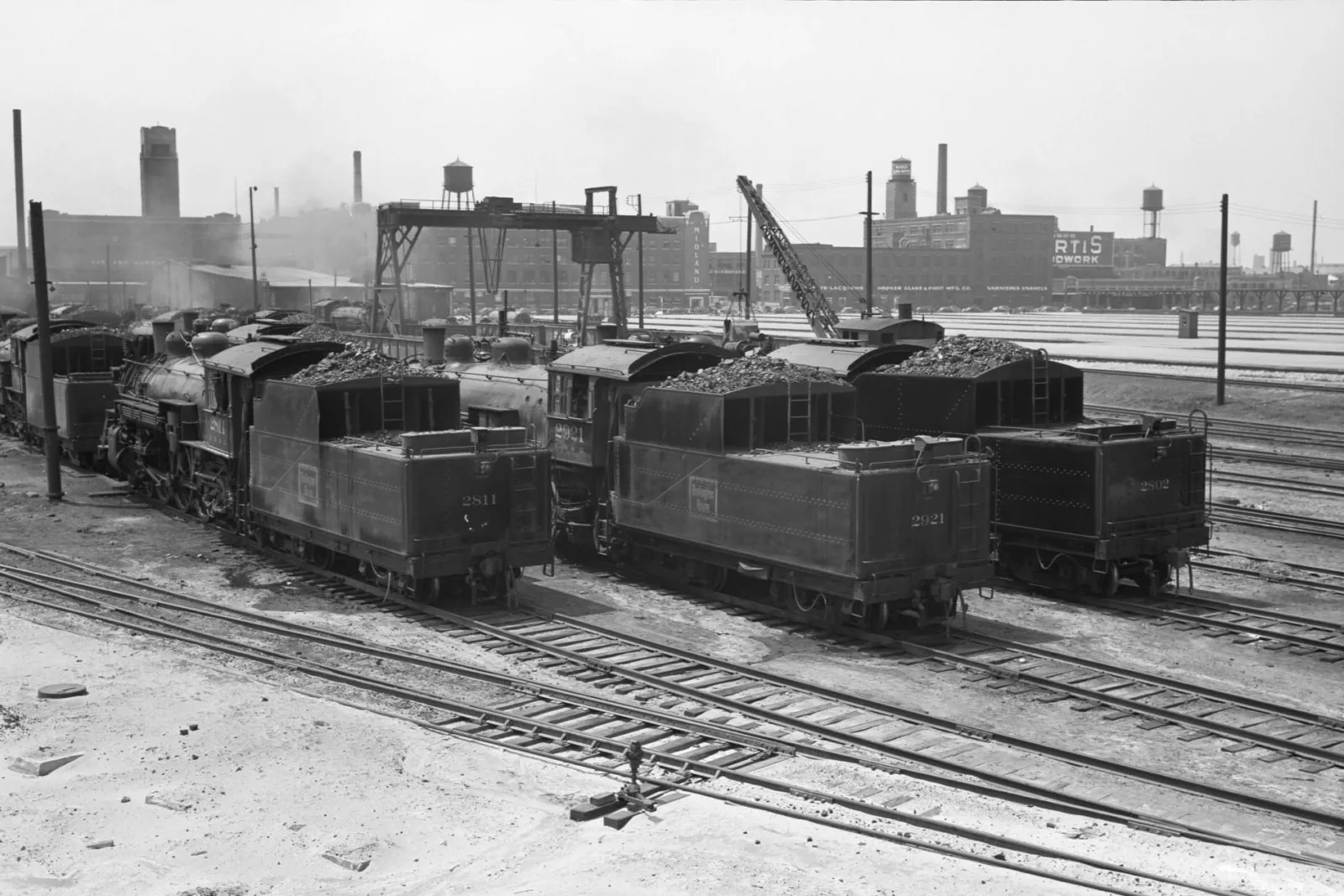 A black and white photograph of a trainyard.