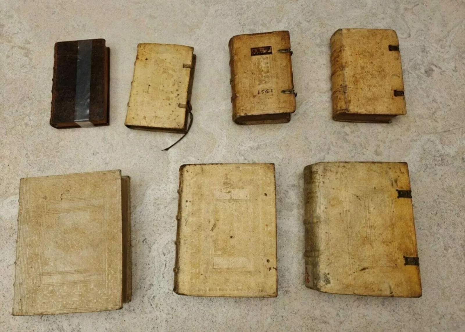 Seven historic books sit on a table top.